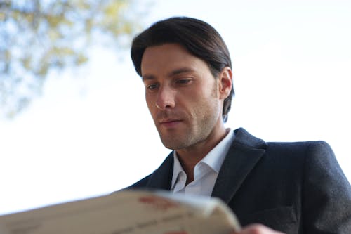 Man in Black Suit Reading Newspaper