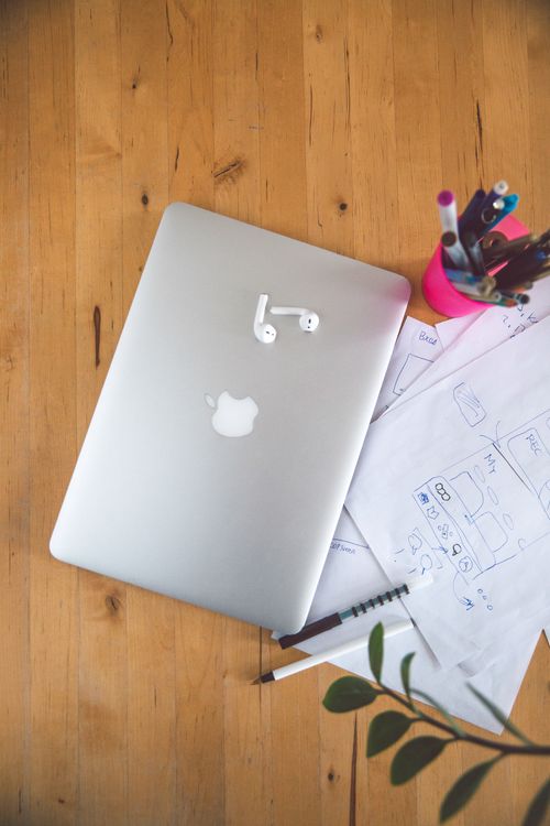 Free Overhead view of a laptop, earbuds, and office supplies on a desk for a productive workspace. Stock Photo