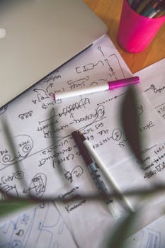 这是一个创意工作空间的顶视图，画面中包含一台笔记本电脑、一支钢笔和一张手绘草图