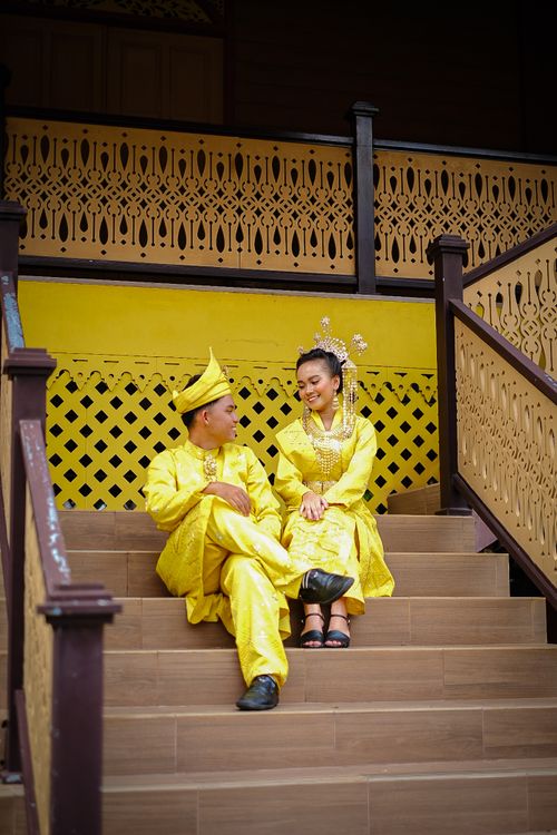 Free Couple in traditional Malay attire sitting on ornate staircase in Jakarta. Stock Photo