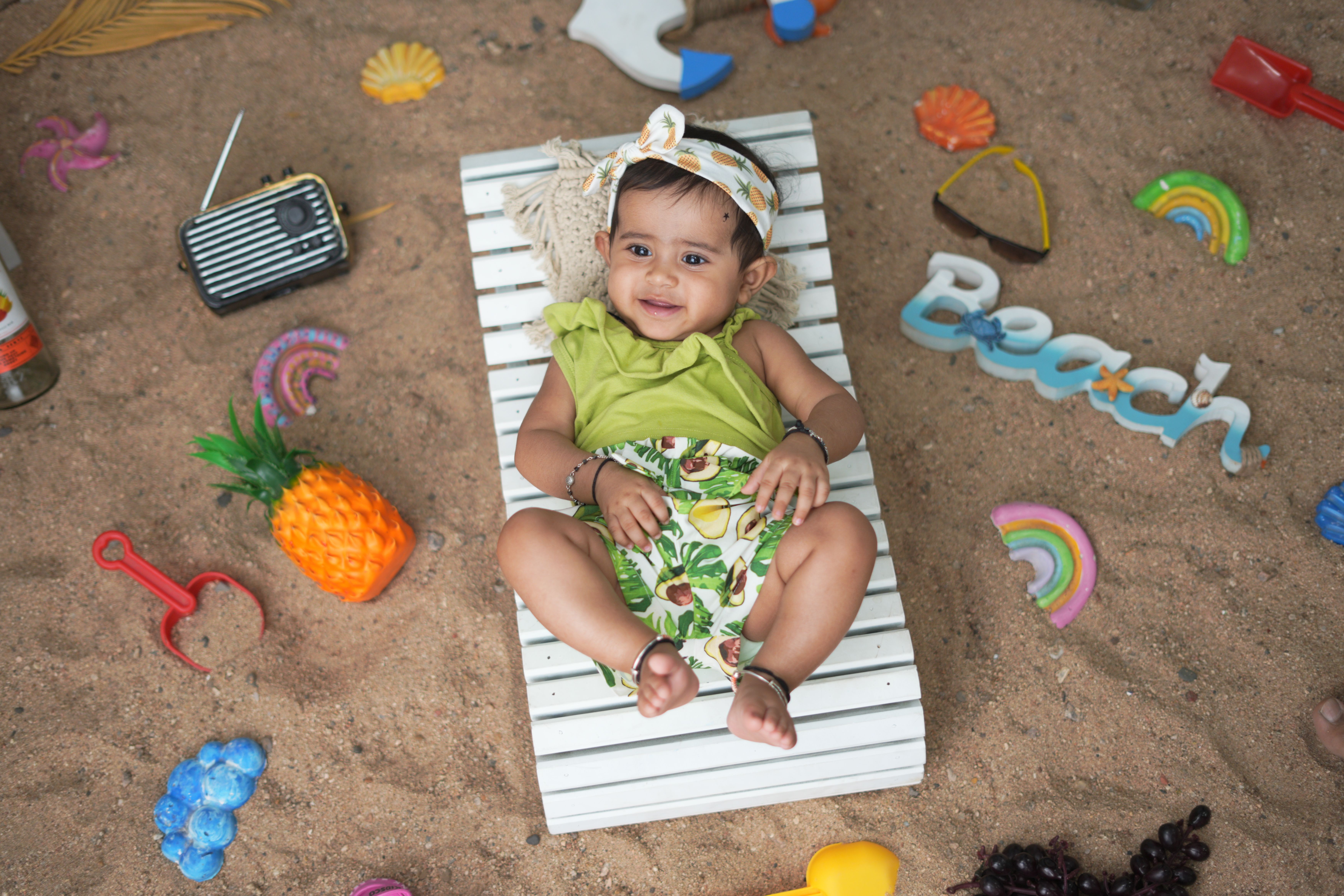 Bébé jouant sur le sable entouré de jouets de plage colorés