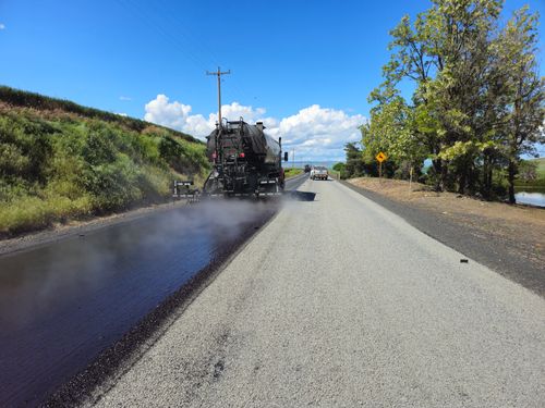 Free Asphalt paver resurfacing a rural road under a bright blue sky in Idaho. Stock Photo