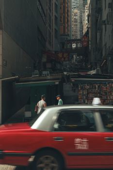 Vibrant city street with a classic red taxi in motion, capturing urban life.