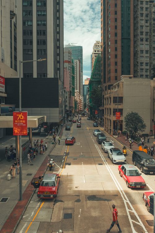 Free A lively city street scene featuring classic red taxis and pedestrians under a clear sky. Stock Photo