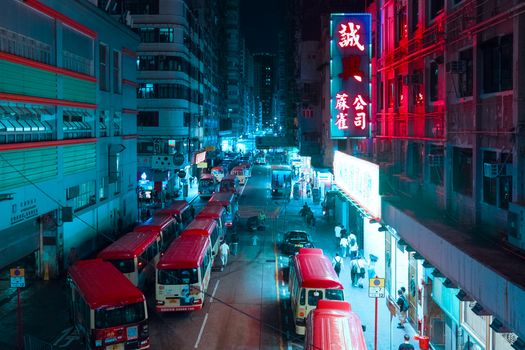 Colorful city street at night with buses and neon lights in an urban Asian cityscape