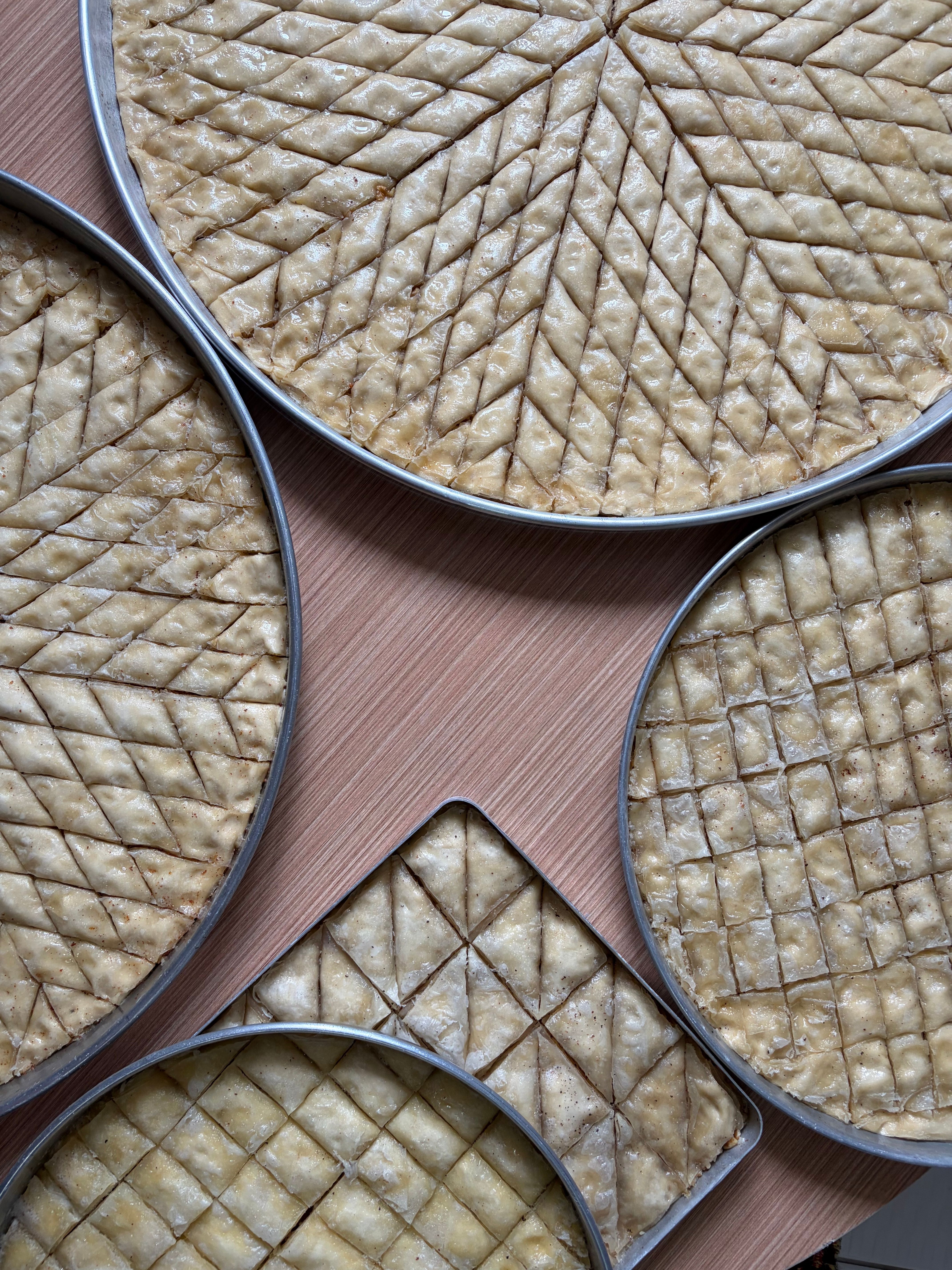 Top view of multiple trays of traditional baklava in geometric patterns.