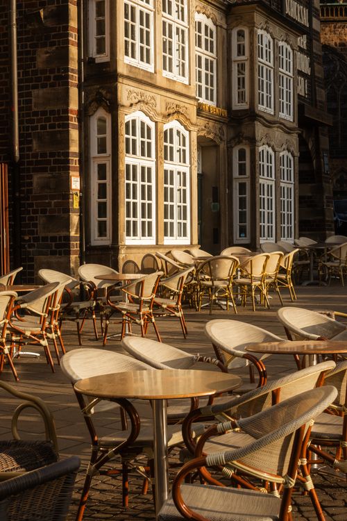 Free Sunlit outdoor cafe seating with vintage architecture in the background. Stock Photo