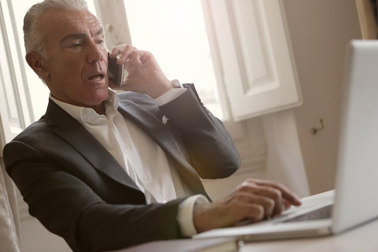 Man In Black Suit Jacket Is Talking On The Phone