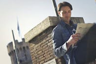 在有历史背景的晴天，读报纸的人户外反对砖墙