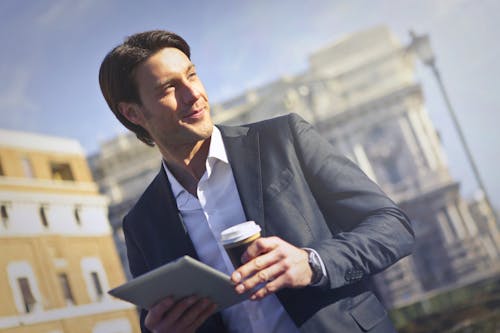 Man In Black Suit Holding A Gadget