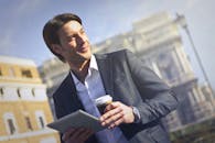 商人在户外自信地使用平板电脑和咖啡