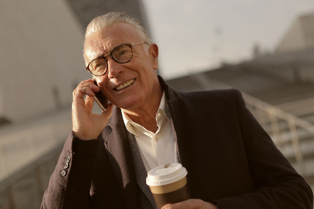 A coach smiling on the phone with a coffee