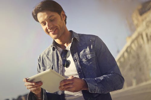 Man In Blue Denim Jacket Holding A Gadget