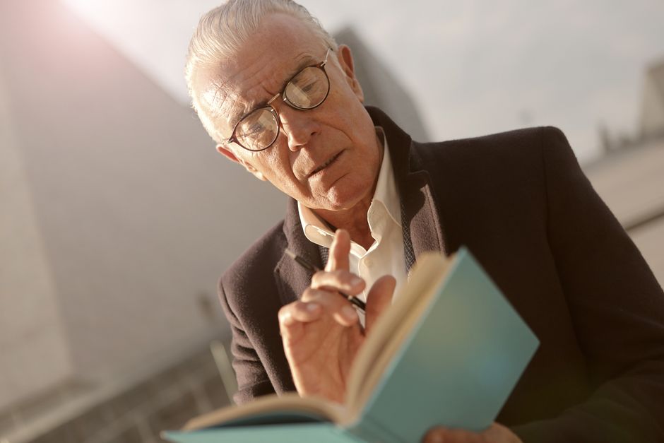 Pessoa idosa concentrada em livro estimulando a memória e a cognição