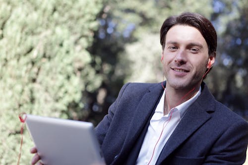 Gratis Hombre Sujetando Una Tableta De Plata Escuchando MÃºsica Foto de stock