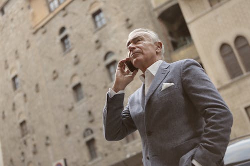 Free Man In Gray Suit Holding A Smartphone Stock Photo
