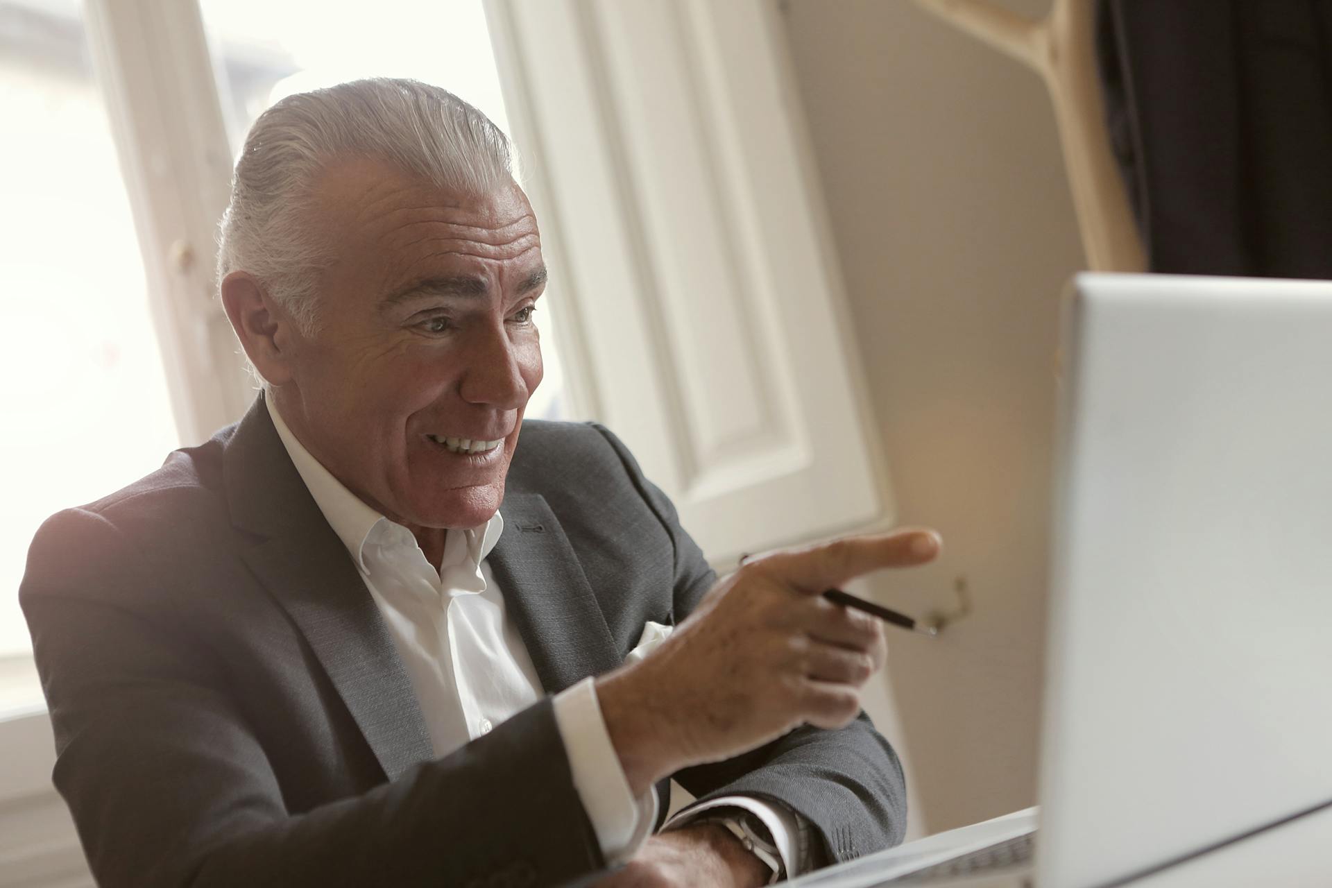 Mature businessman in office suit actively engaging during a digital meeting.