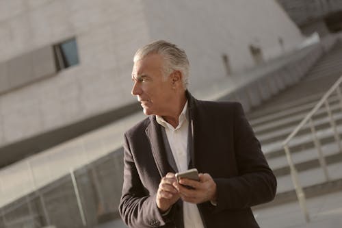 Man In Business Attire Holding A Smartphone