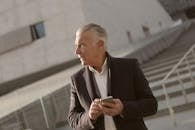 在现代户外环境中，高级商人自信地使用智能手机