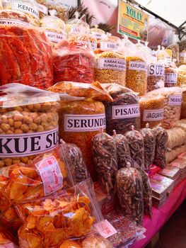 Vibrant display of traditional Indonesian snacks at a bustling street market.