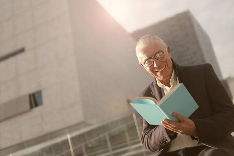 Man In Black Coat Is Reading A Story Book 