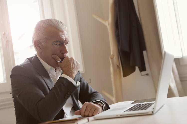 Man In Black Suit  Leaning On White Table