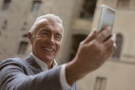 快乐的老年人在户外用智能手机自拍时微笑着