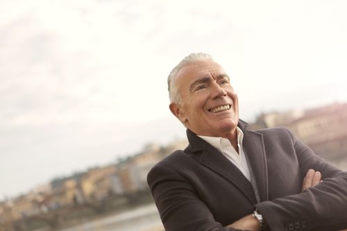 Free A senior man in business attire smiles confidently during a sunny outdoor setting. Stock Photo