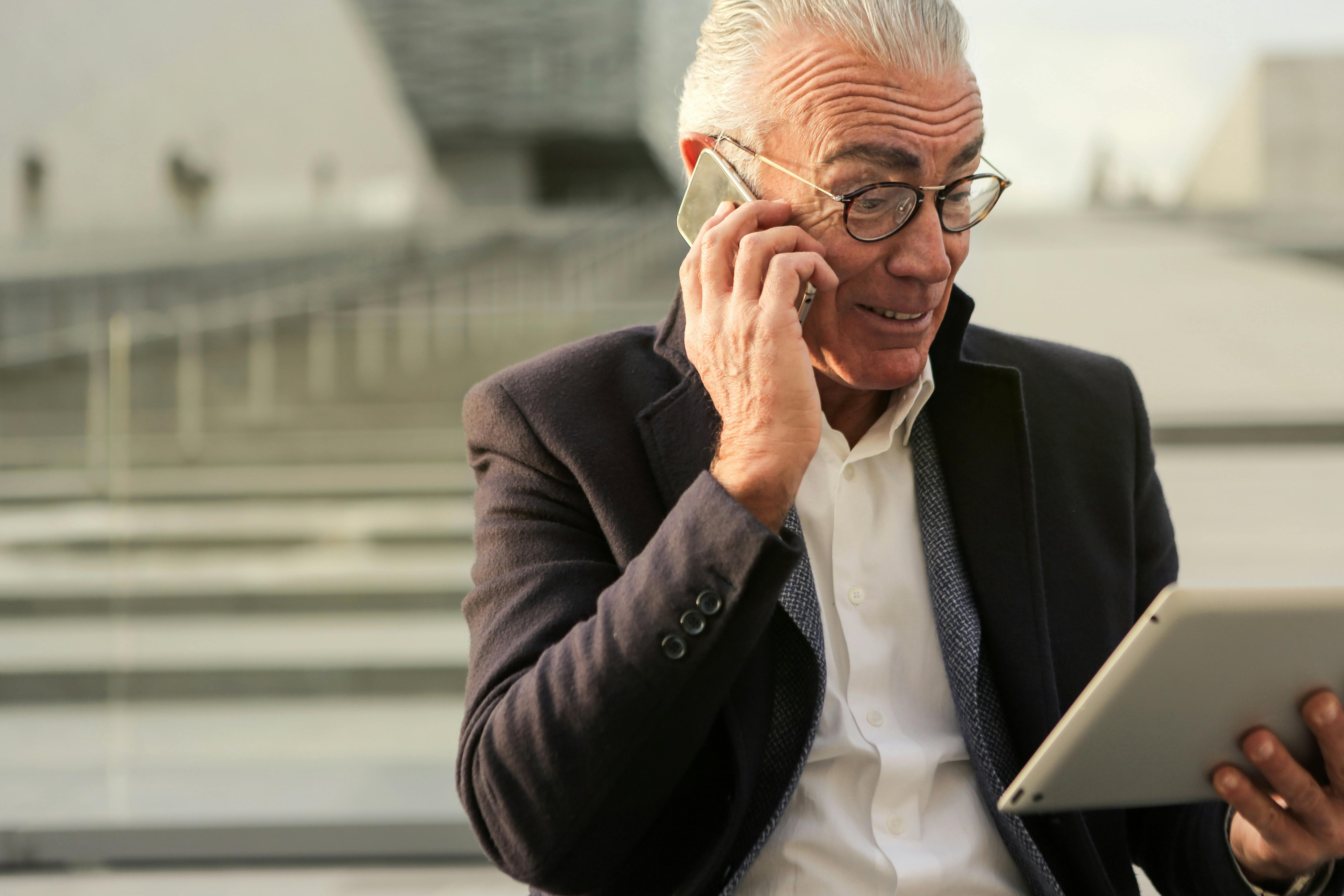 man in black suit holding a mobile