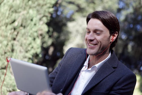 Free Smiling Man In Black Suit Using A Gadget Stock Photo