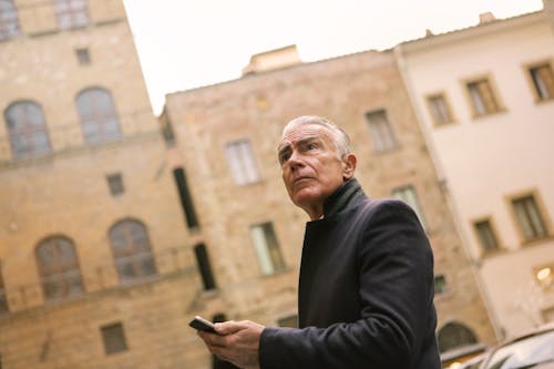 Free Man In Black Coat Holding A Mobile Stock Photo
