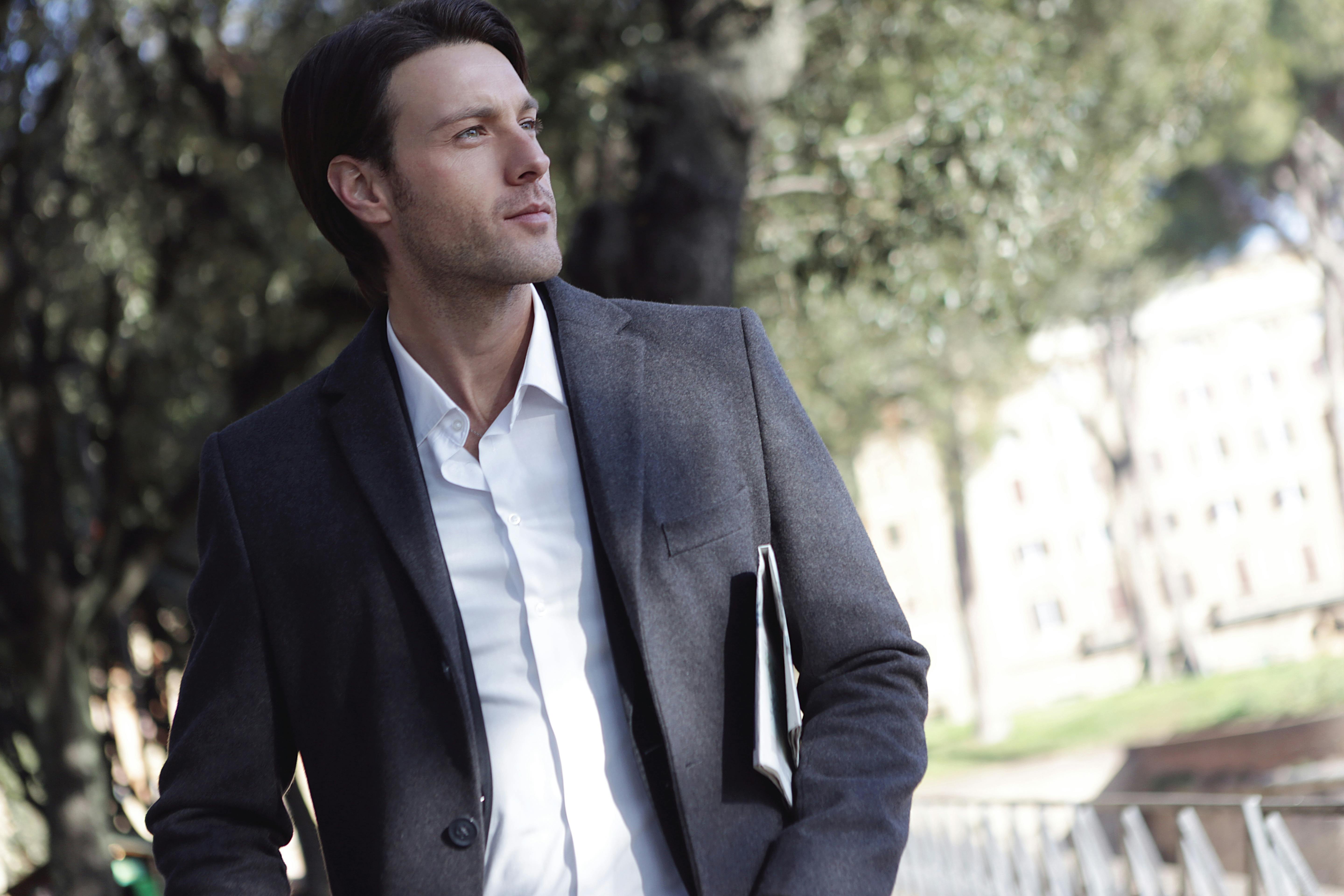 一位穿着正式服装的优雅年轻人，自信地站在户外