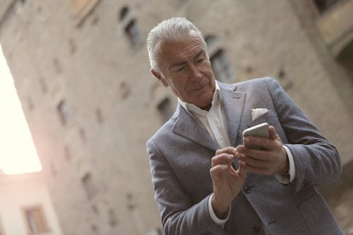 Man In Gray Suit Holding A Smartphone