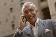 身着职业装的中年商人，在户外用智能手机交谈时露出微笑