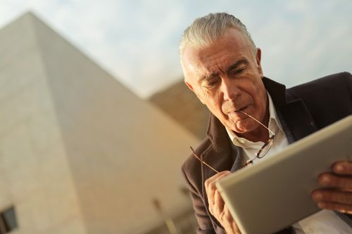 Free Senior man focusing on digital tablet outdoors. Concept of technology and leisure. Stock Photo