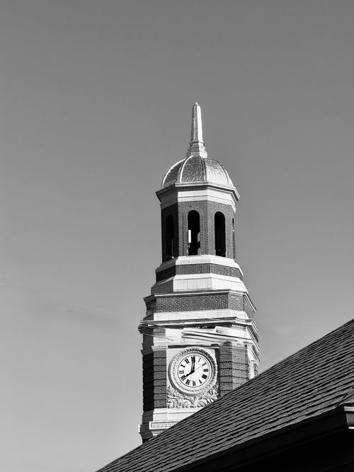Free Black and white photo of a historic clock tower under a clear sky, showcasing architectural details. Stock Photo