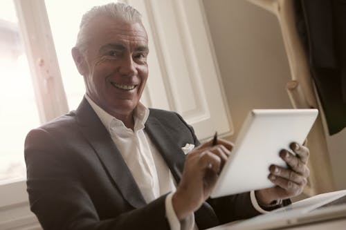 Free Man In Black Suit Holding A Gadget Stock Photo