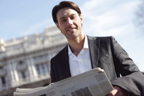 Man In Black Suit Holding A Newspaper