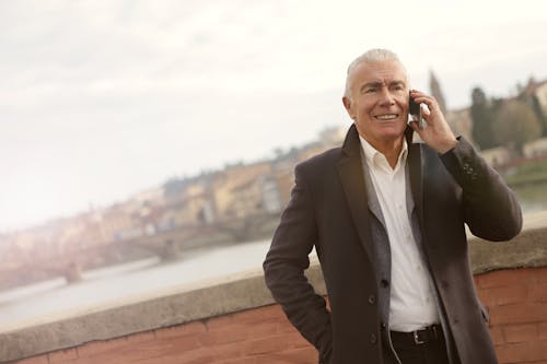 Man in Black Suit Standing Beside Brick Wall