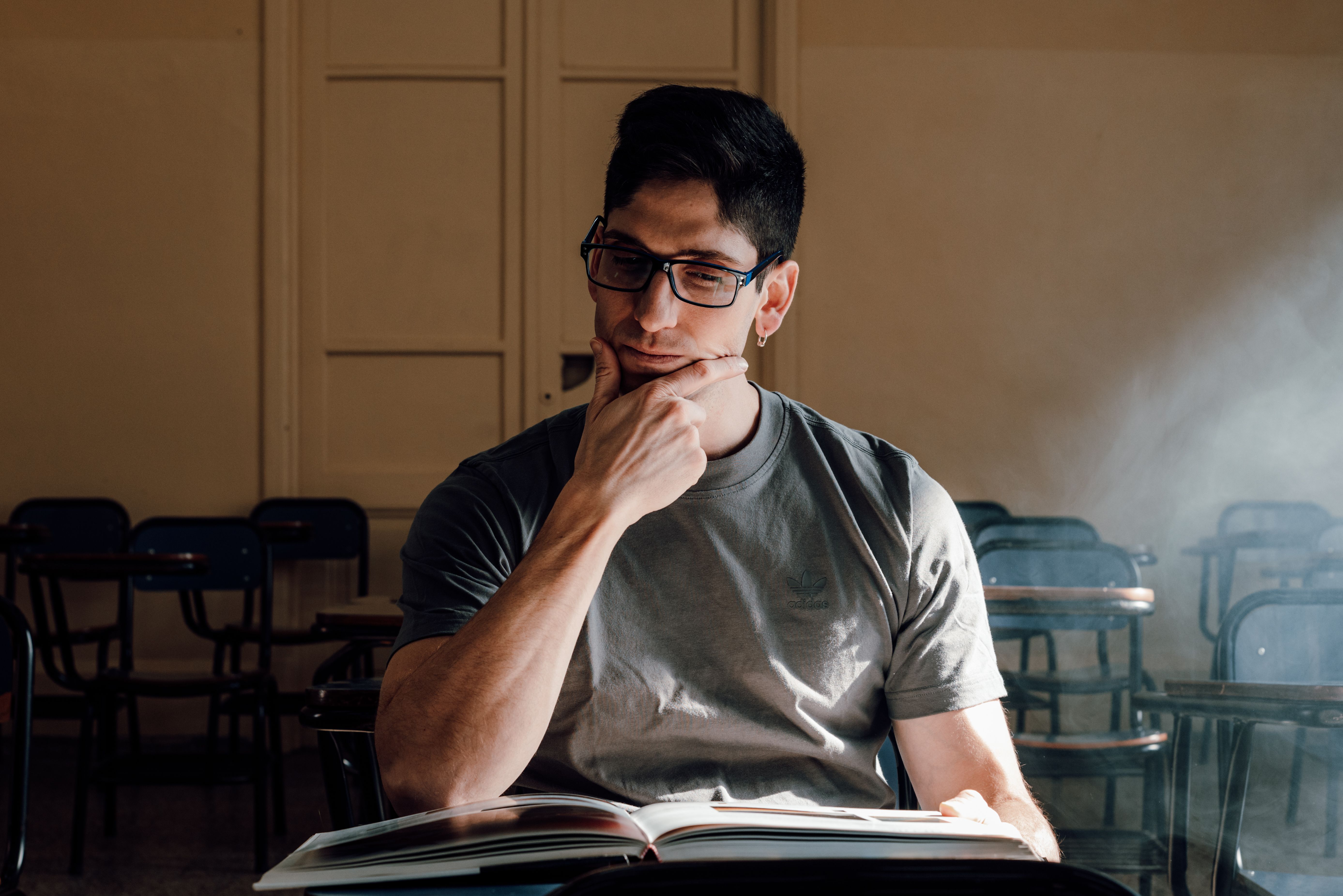 A young man in a classroom setting, deeply focused on an open book in Buenos Aires, Argentina.