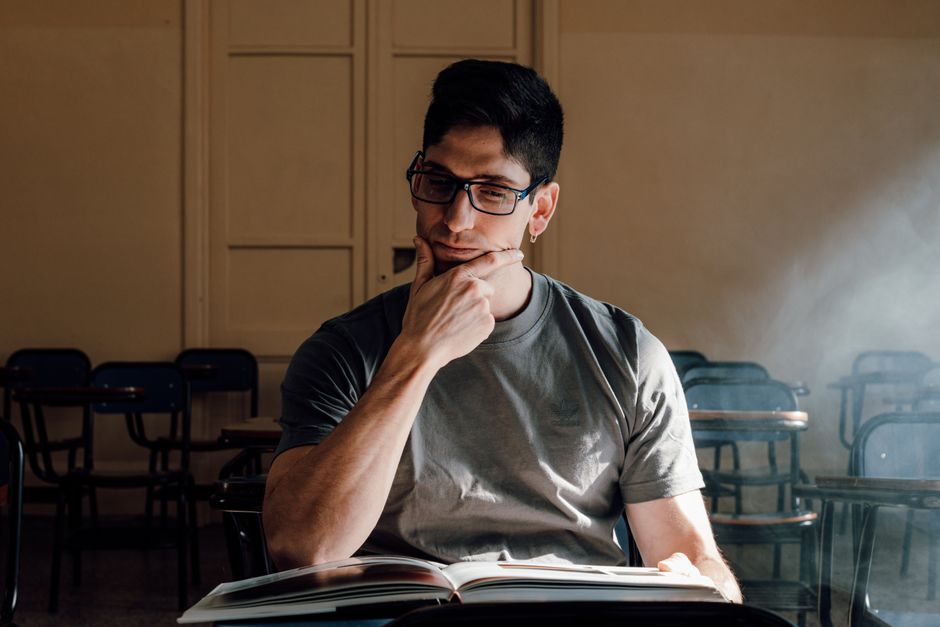 A young man in a classroom setting, deeply focused on an open book in Buenos Aires, Argentina. A young man in a classroom setting, deeply focused on an open book in Buenos Aires, Argentina.