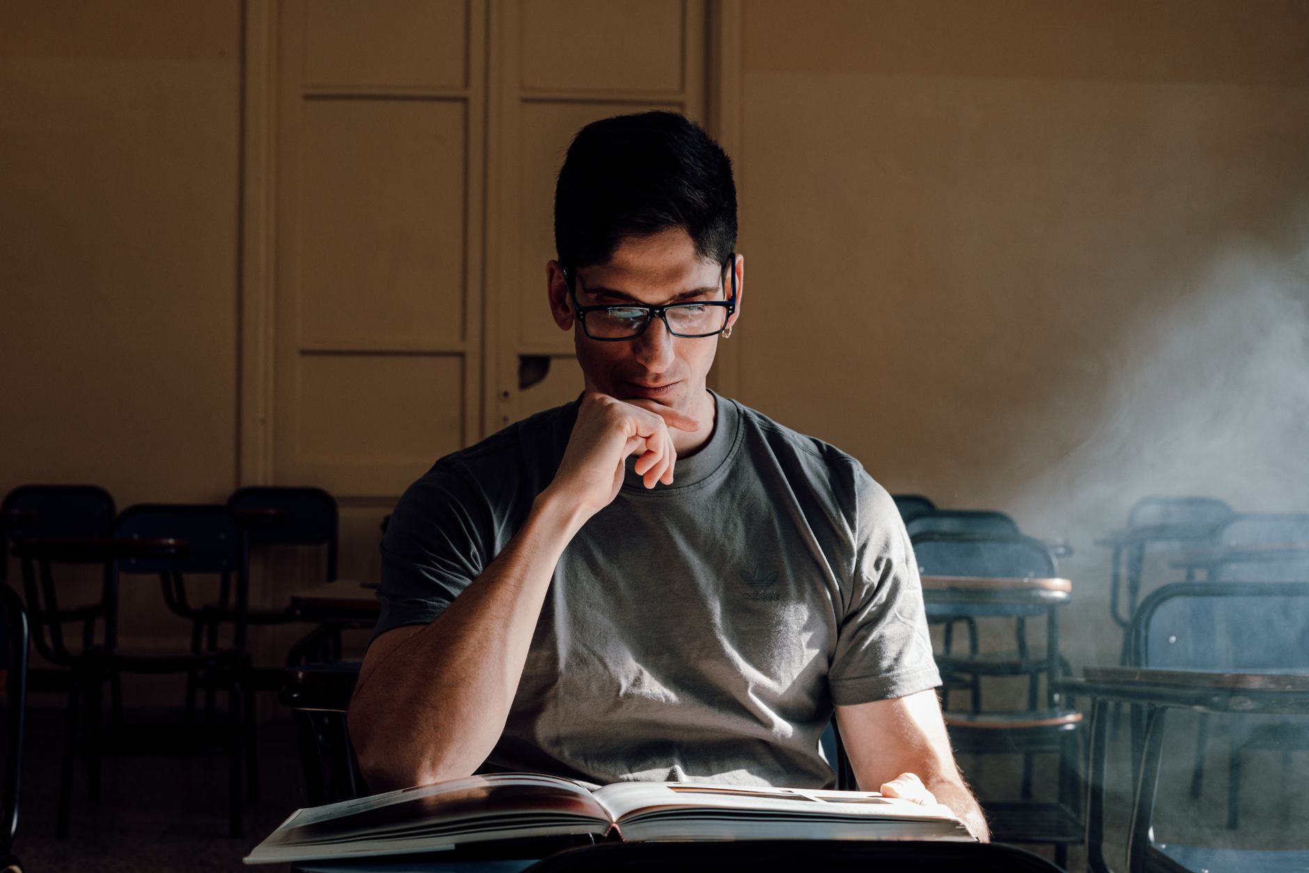 A young man reads intently in a sunlit Buenos Aires classroom, embodying focused academic study.