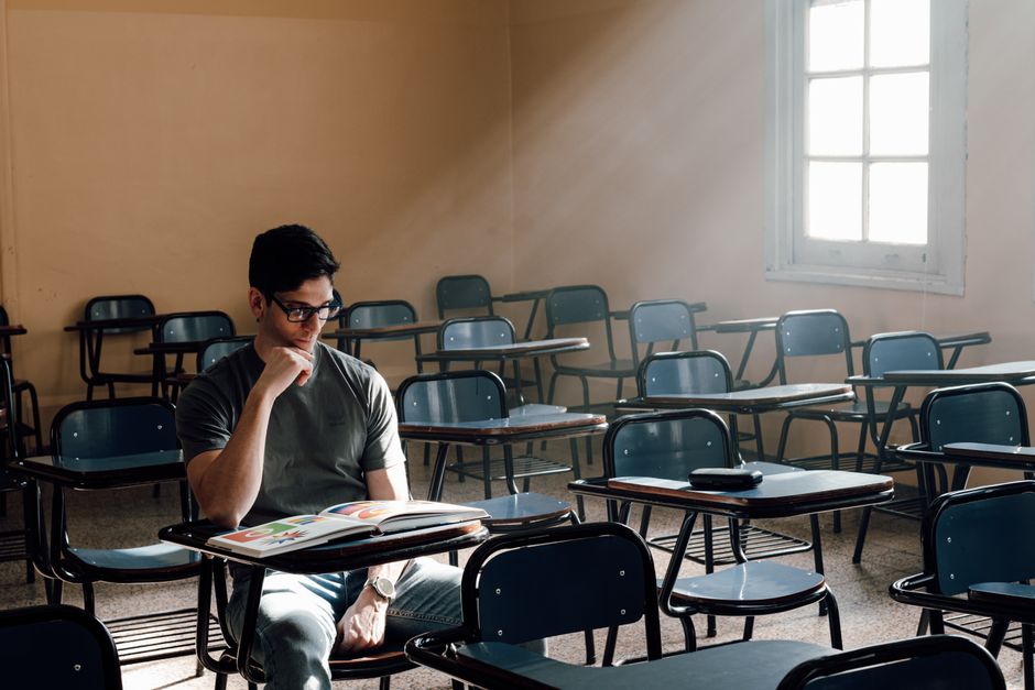 Transforme sua Vida com a Criatividade: 7 Dicas Práticas 2 A person studies alone in an empty classroom with sunlight streaming through the window in Buenos Aires.