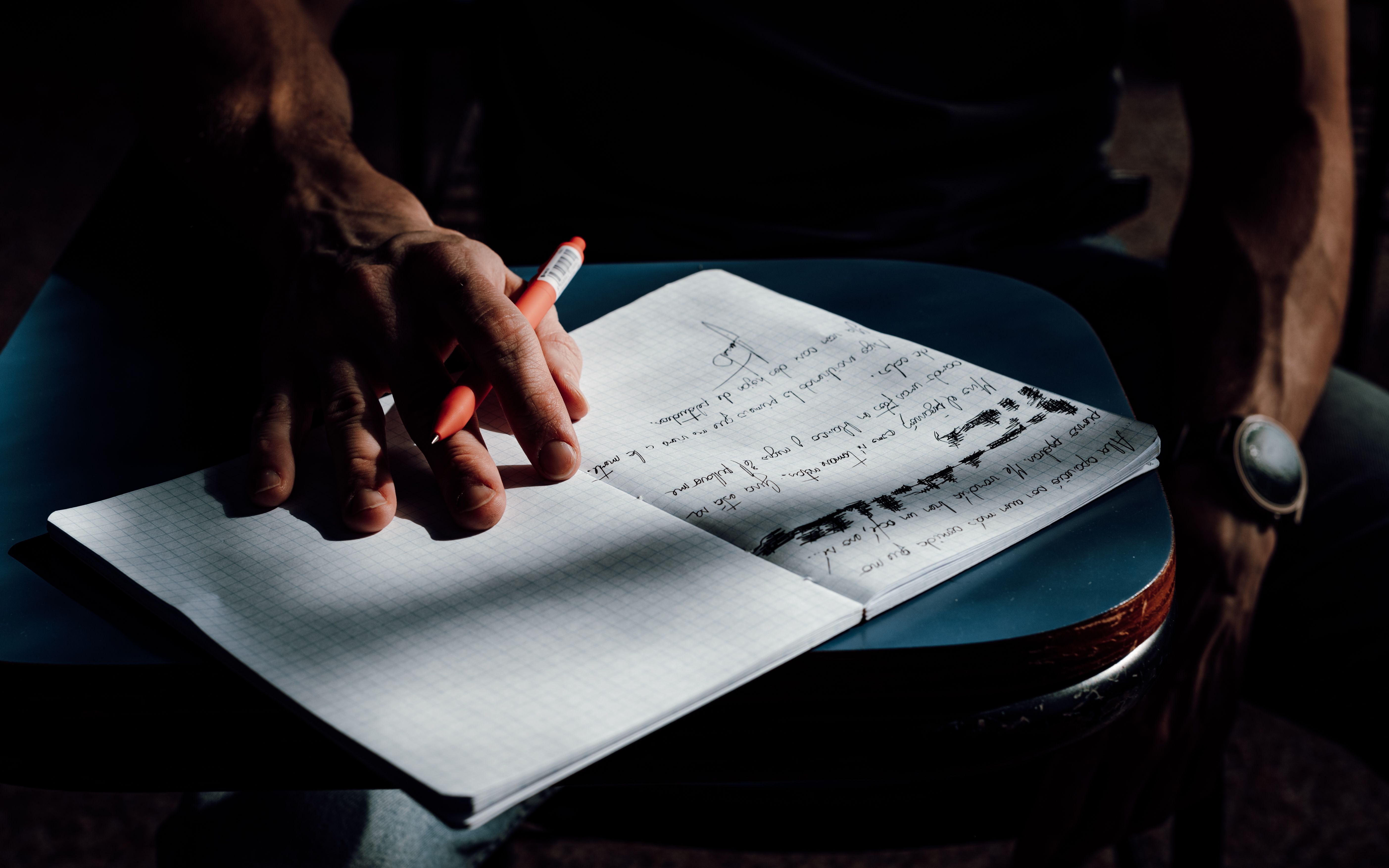 Close-up of a student writing in a notebook with ambient lighting, capturing a moment of academic focus.