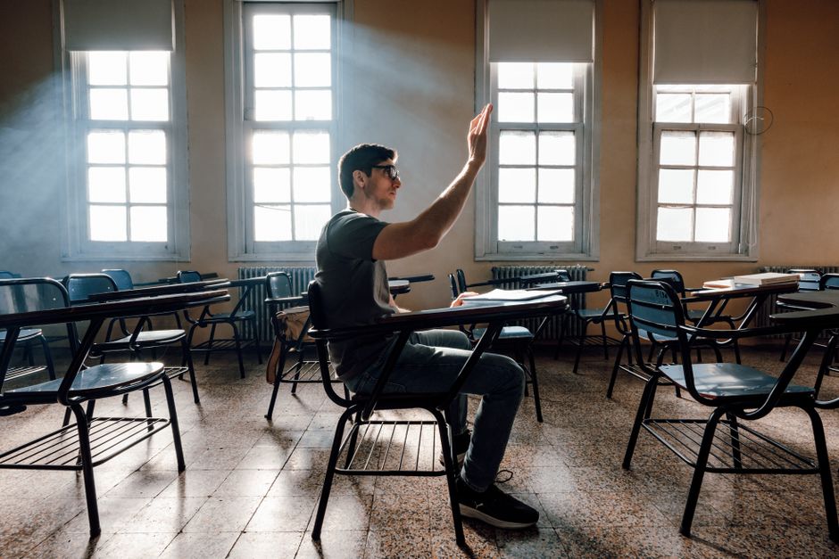 Un estudiante levanta la mano en un aula soleada de Buenos Aires, personificando la vida universitaria y el aprendizaje.