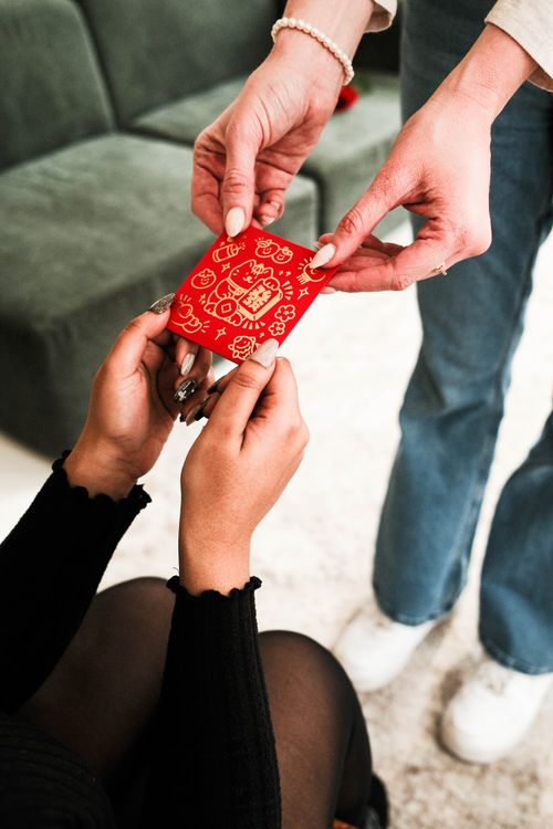 Free Close-up of hands exchanging a traditional red envelope indoors. Stock Photo