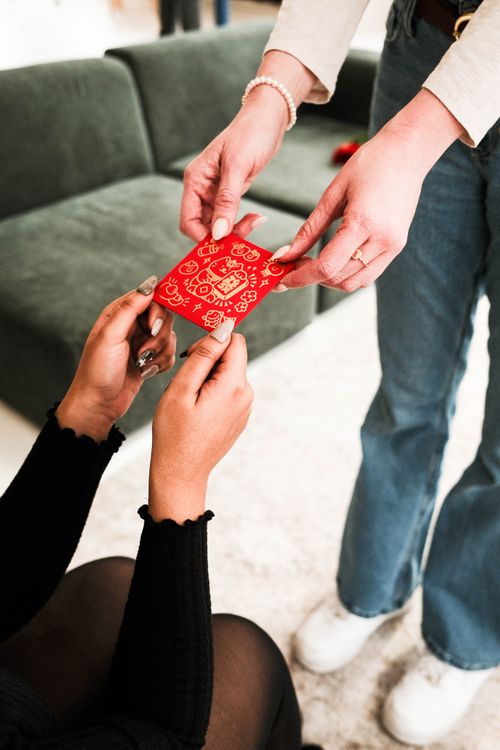 Free Two people exchanging a red envelope in a contemporary living room setting. Stock Photo