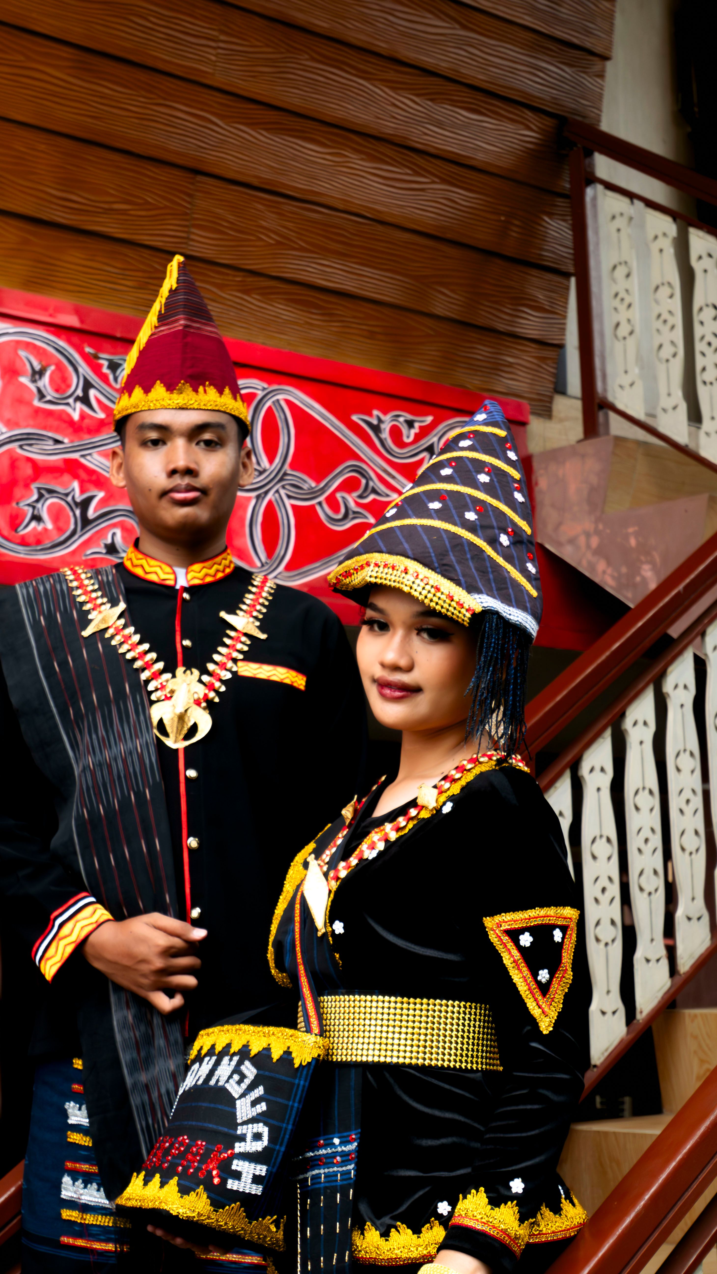 Couple wearing traditional Indonesian attire in cultural setting.