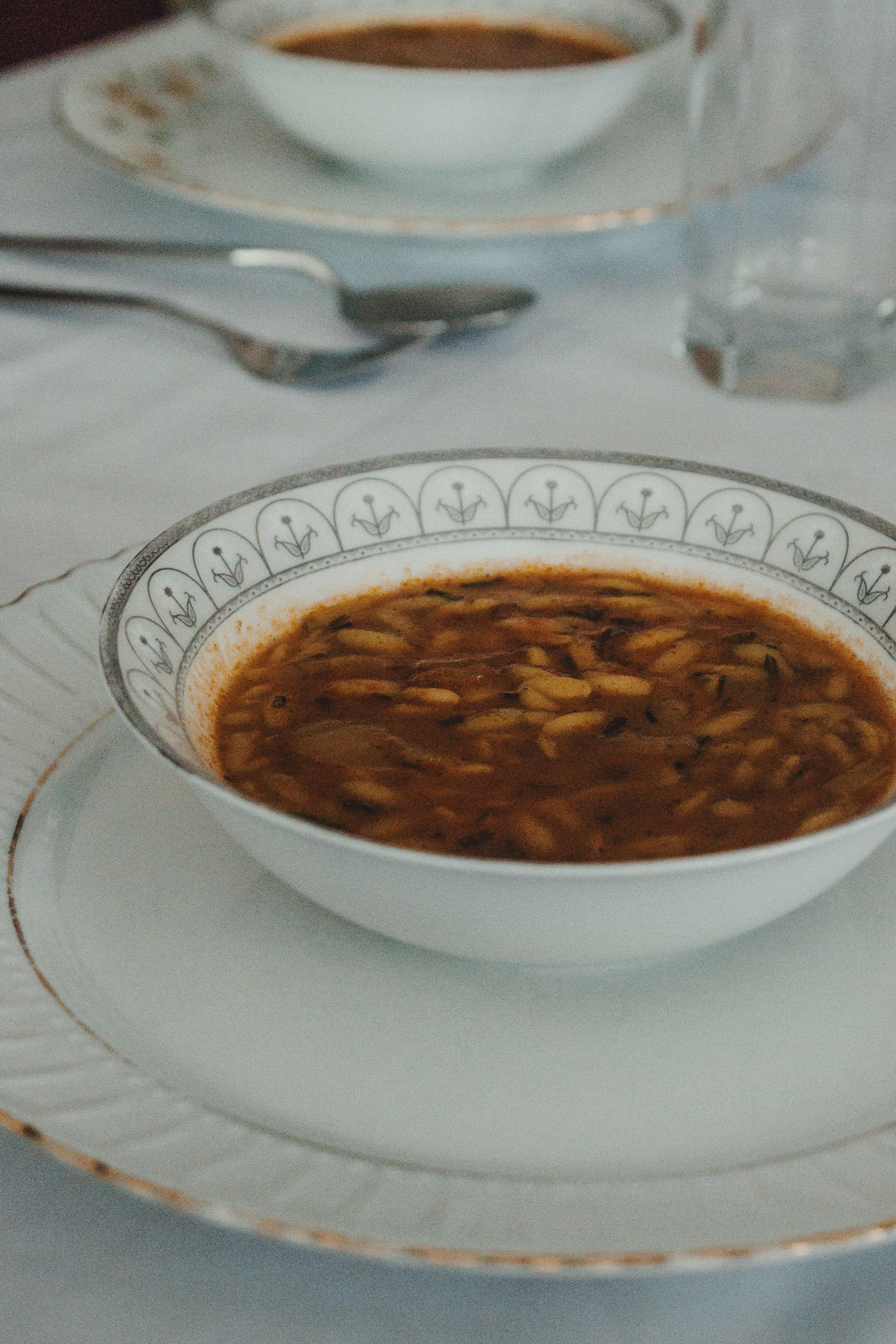 A refined image of a soup bowl on an elegant table setting with fine china.