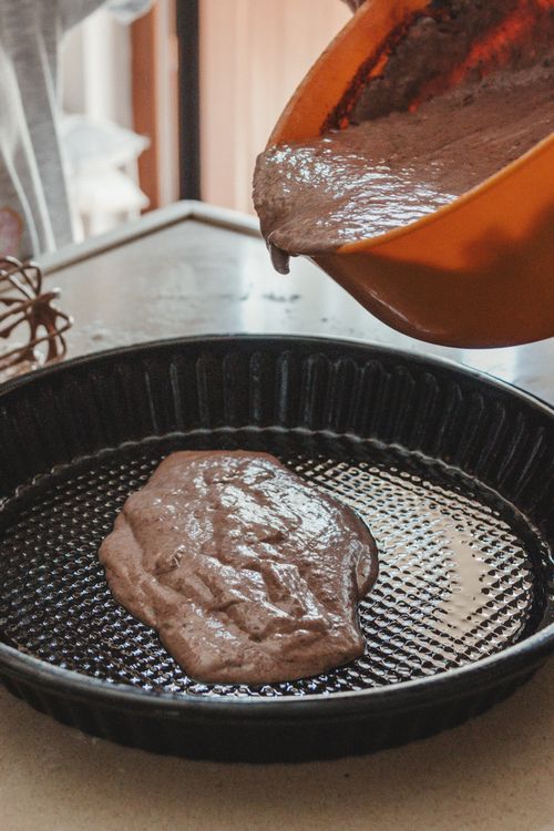 Free Hand pouring chocolate cake batter into a baking pan, ready to bake. Stock Photo